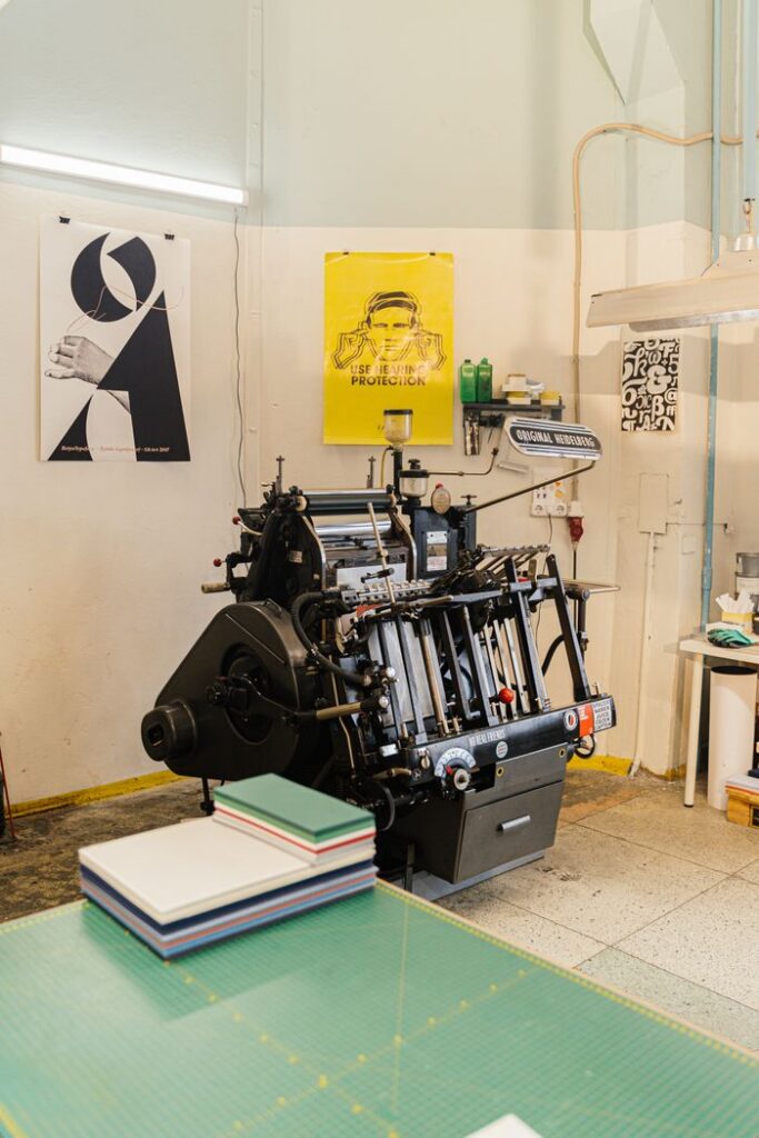 A vintage printing press in a creative design studio with posters and equipment.